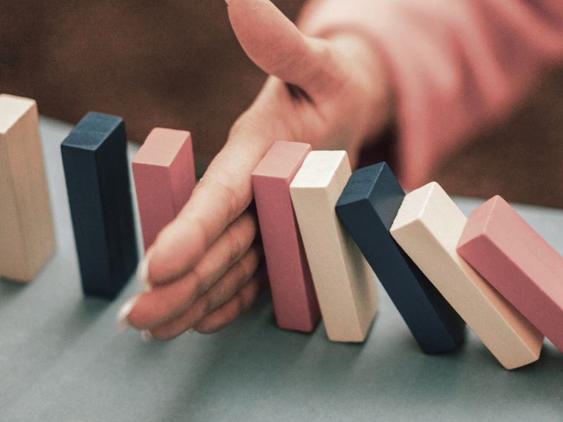 Image of a hand stopping a line of falling dominoes to demonstrate EQ and the Rosenthal Effect